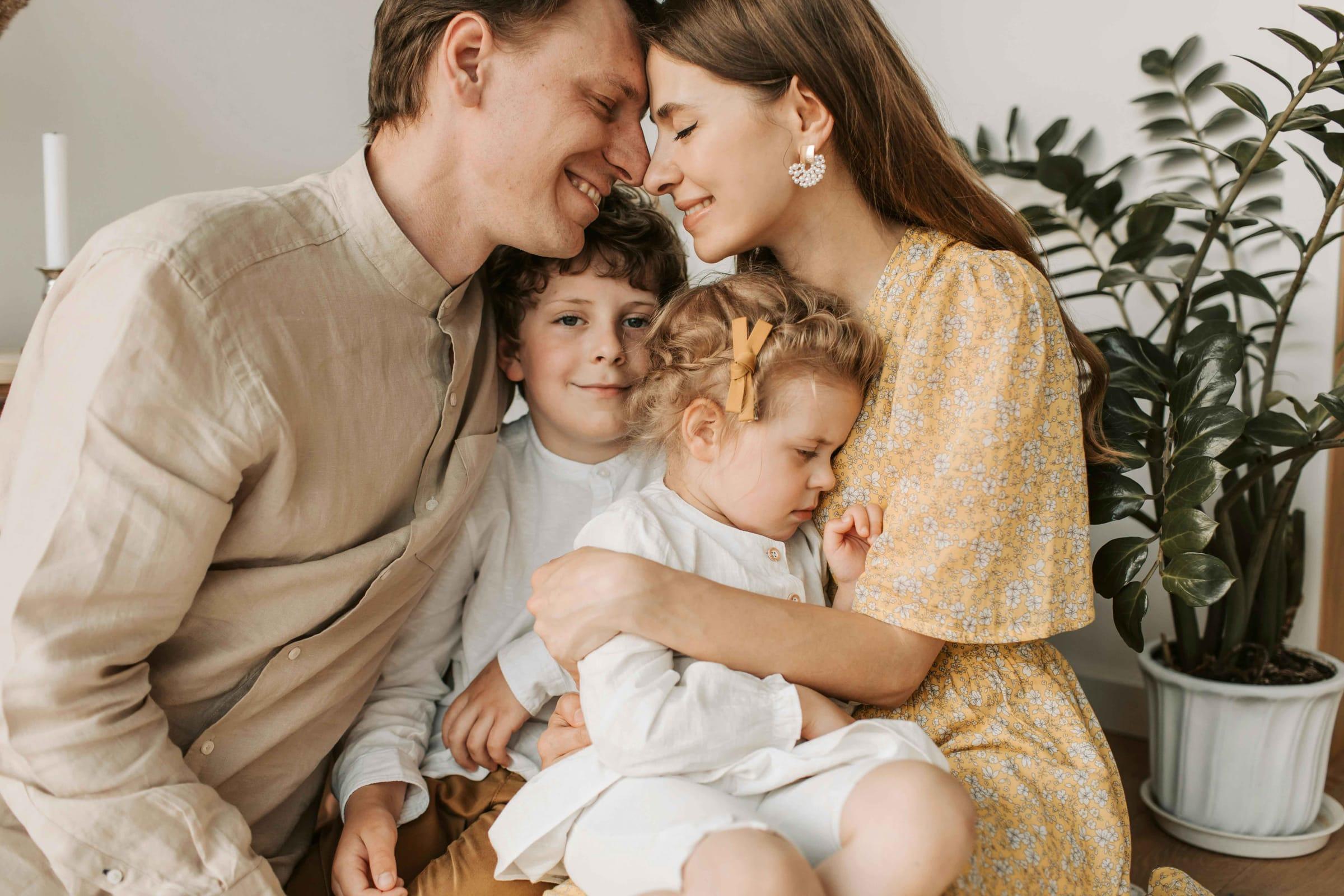 Mother, father and two young children cuddle at home, lifestyle session