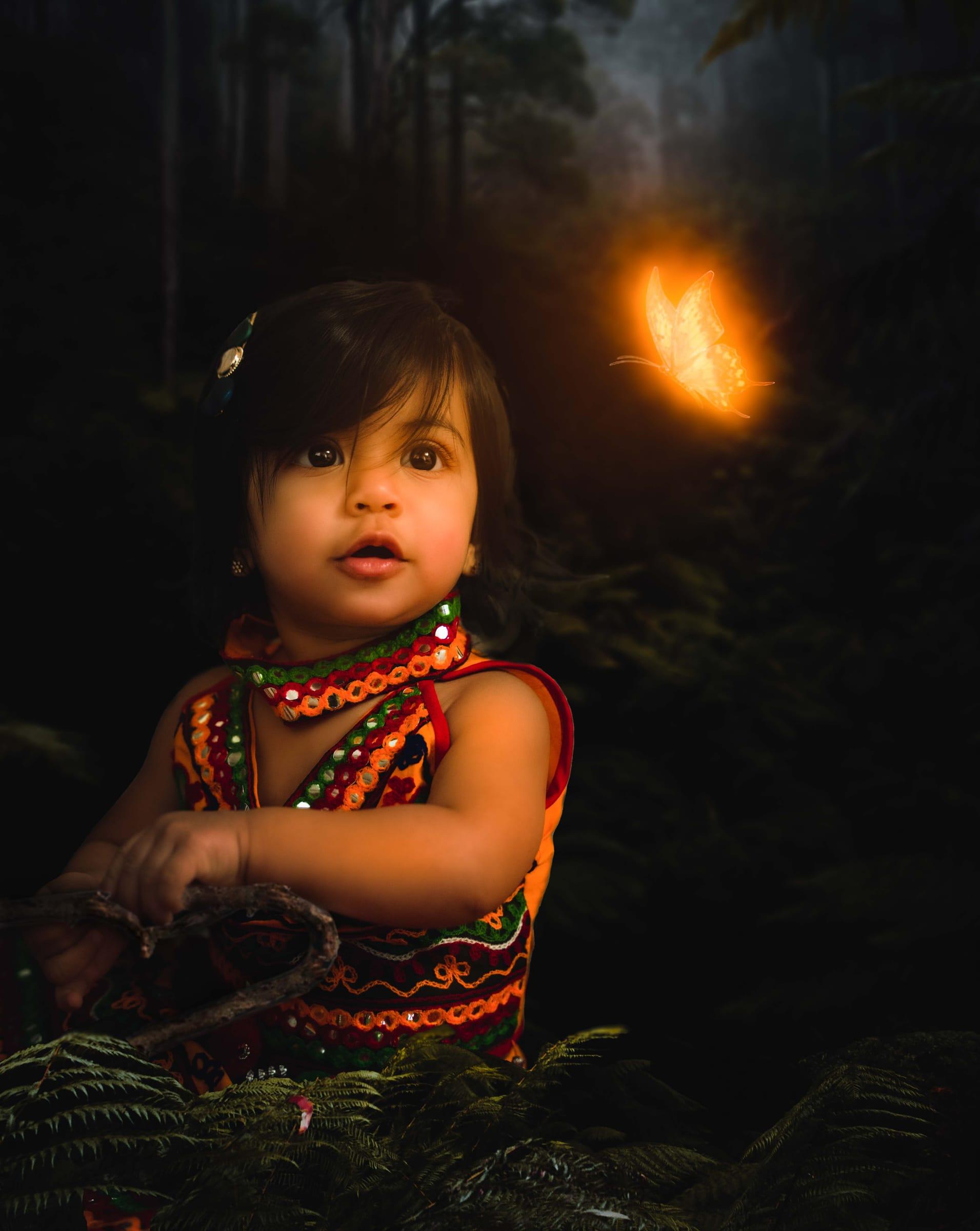 Little girl in a dark forest with a glowing butterfly, creative child portrait