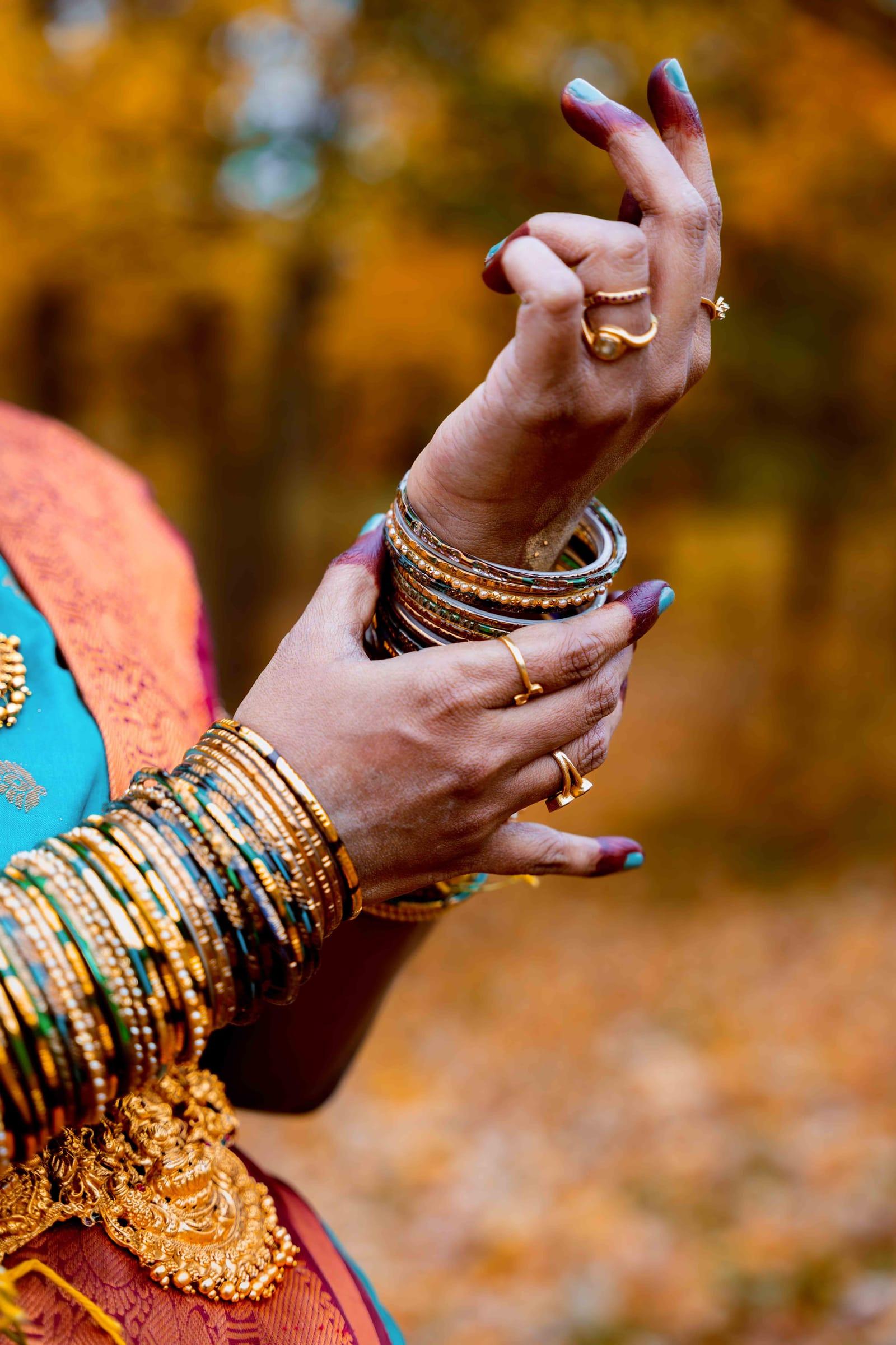 Hands with gold bangles against autumn leaves