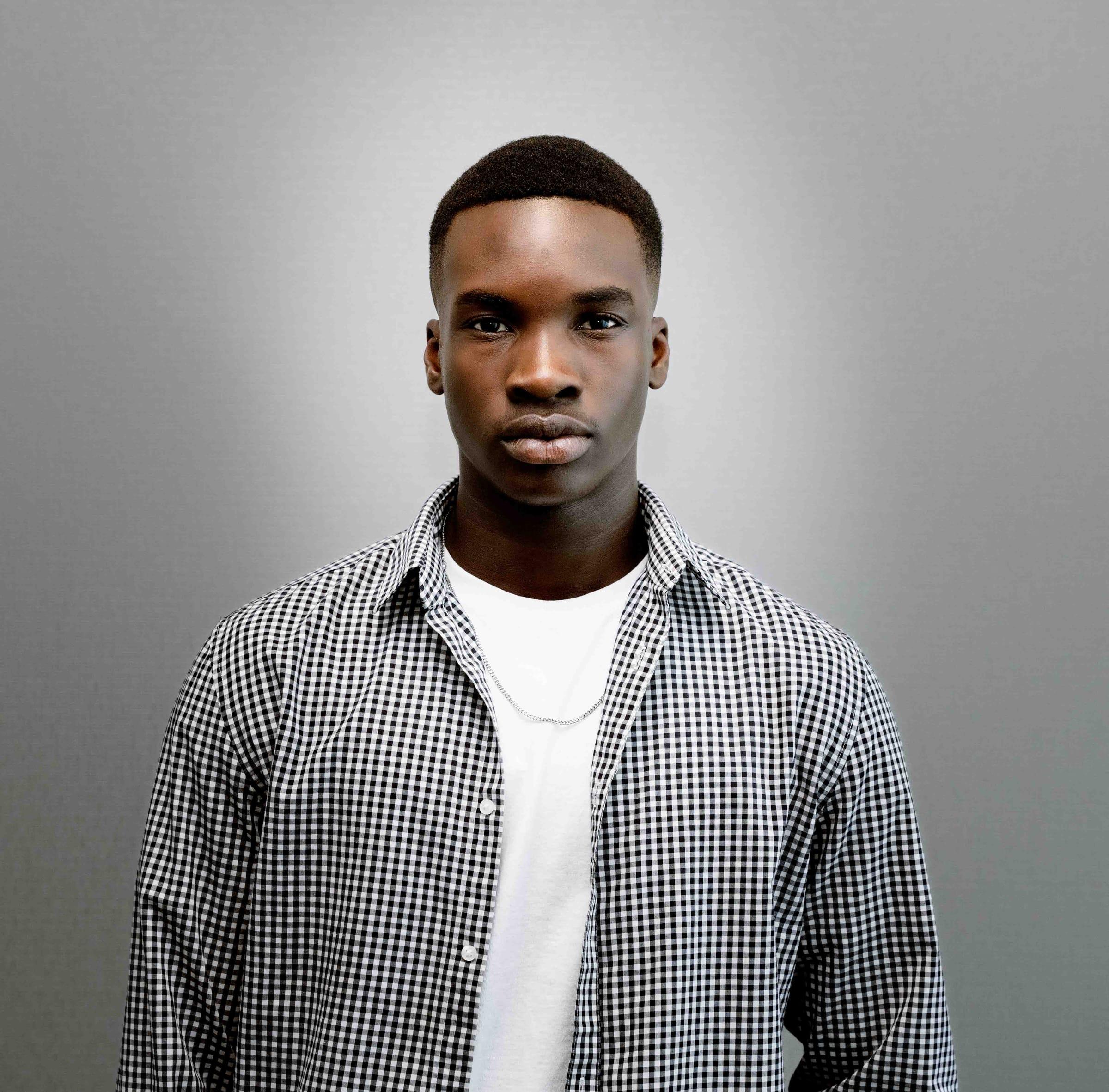 Moody studio portrait of a young man in a gingham shirt