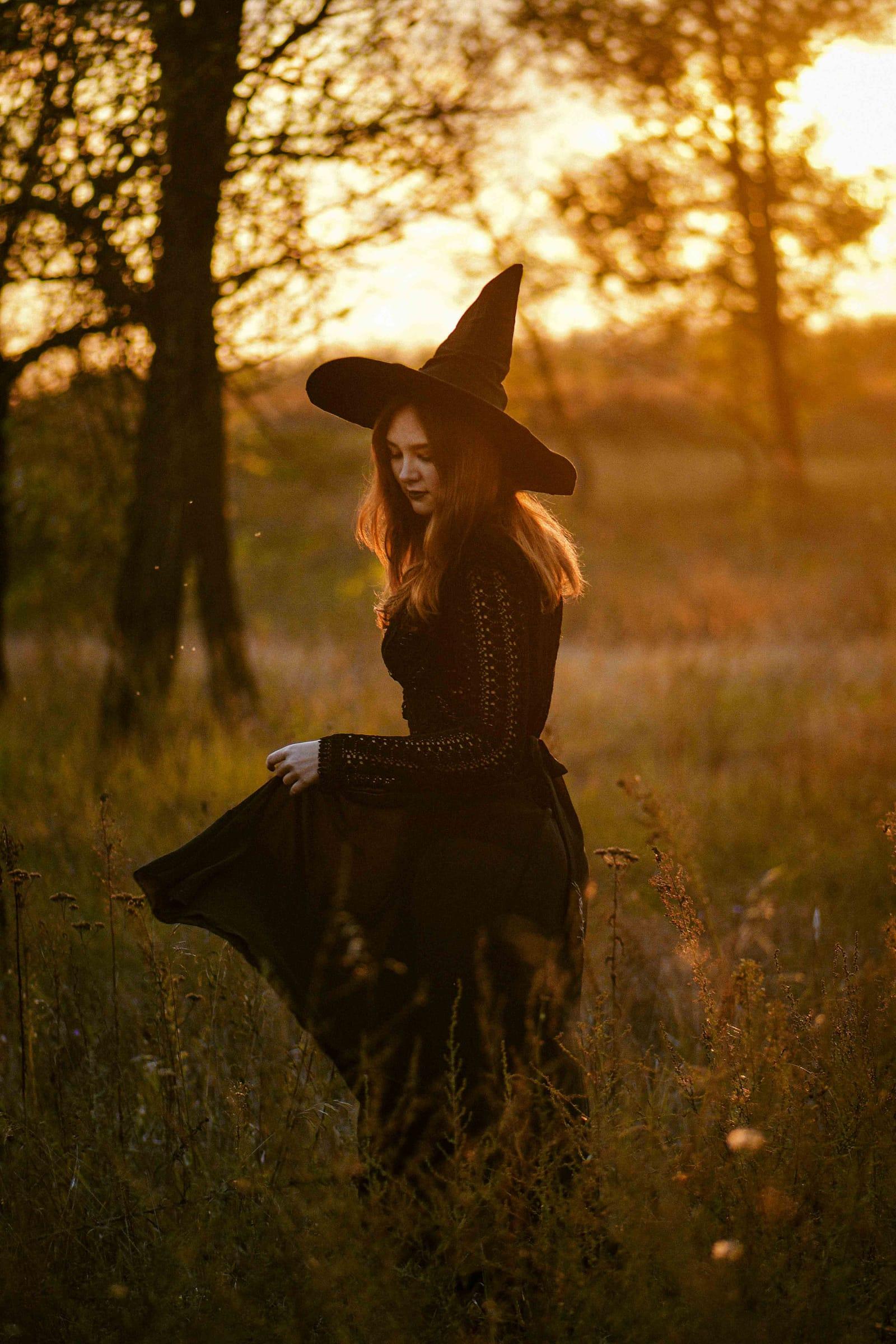 Woman in a witch costume in a golden field, Halloween themed session