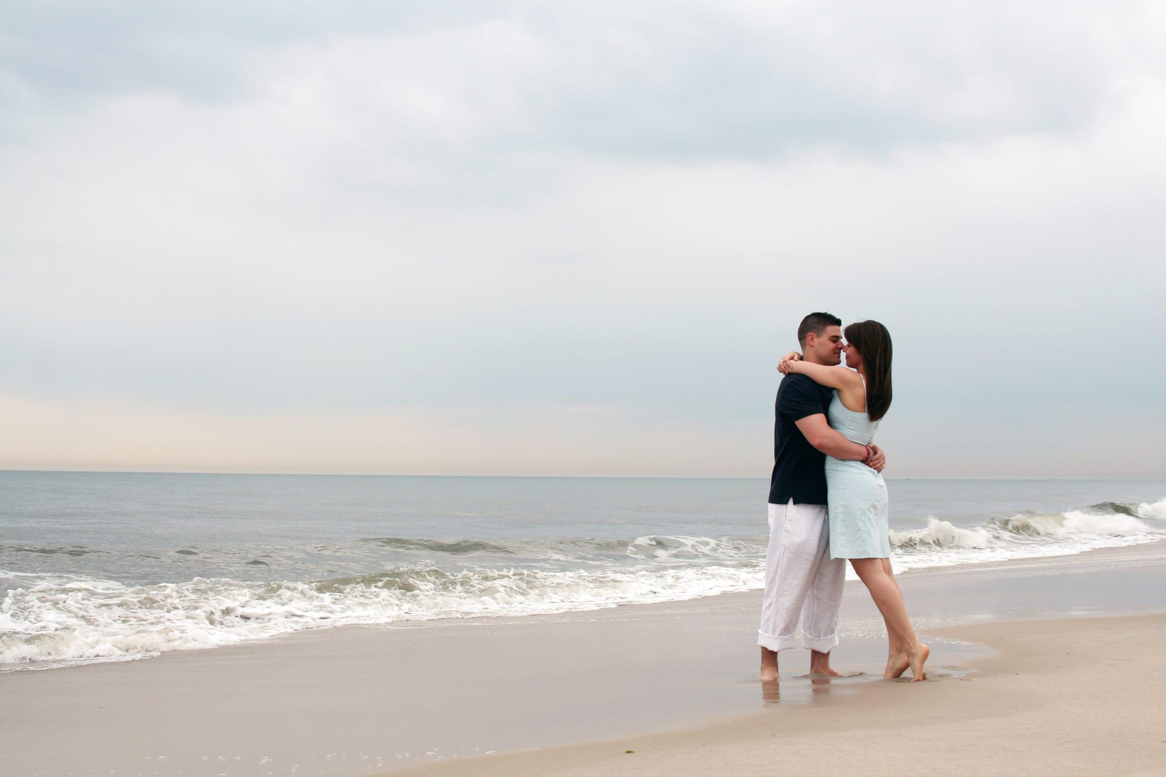 Couple embraces on a Lake Ontario beach during an engagement session